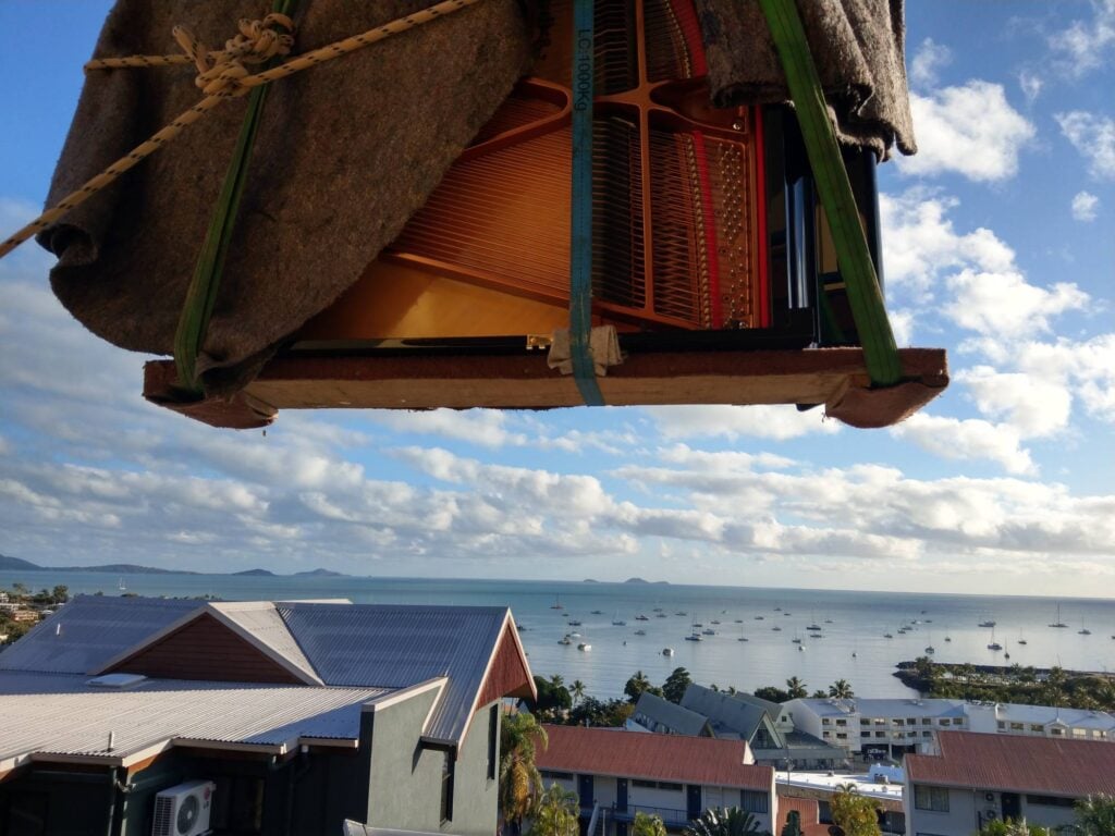 piano removal via crane with scenic coastal view